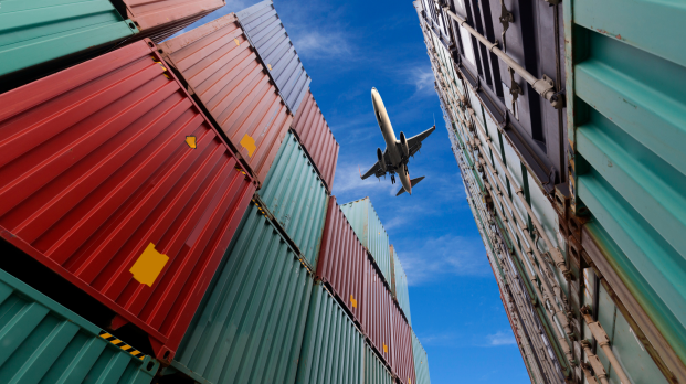 Airplane flying over shipping containers