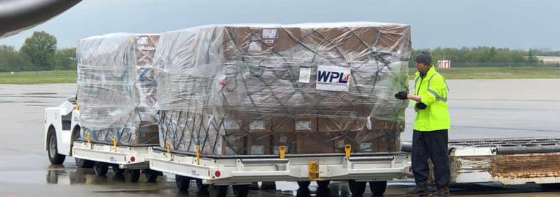 Man holding shipping boxes next to transport truck