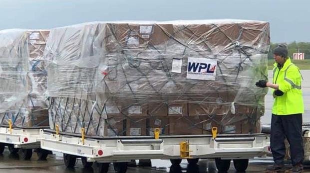 Man holding shipping boxes next to transport truck